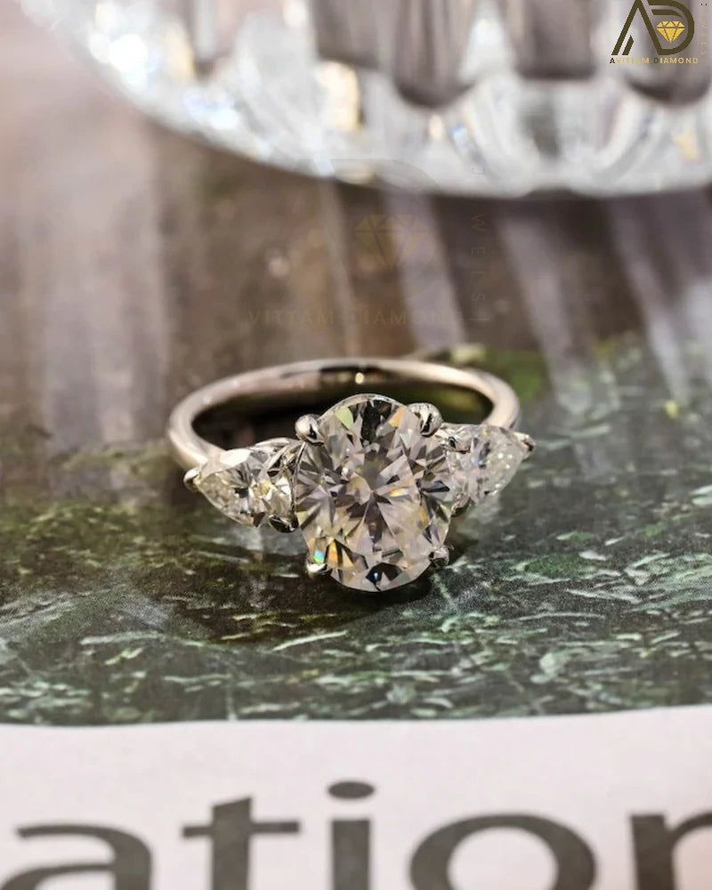 Discover our stunning Three Stone Moissanite Ring featuring an elegant oval cut center stone and pear cut side stones. A perfect choice for weddings or engagements!