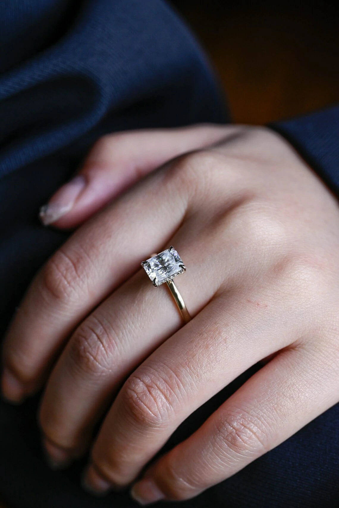 Stunning moissanite solitaire ring with radiant cut stone in yellow gold. Features a hidden halo for subtle glam and brilliant shine.