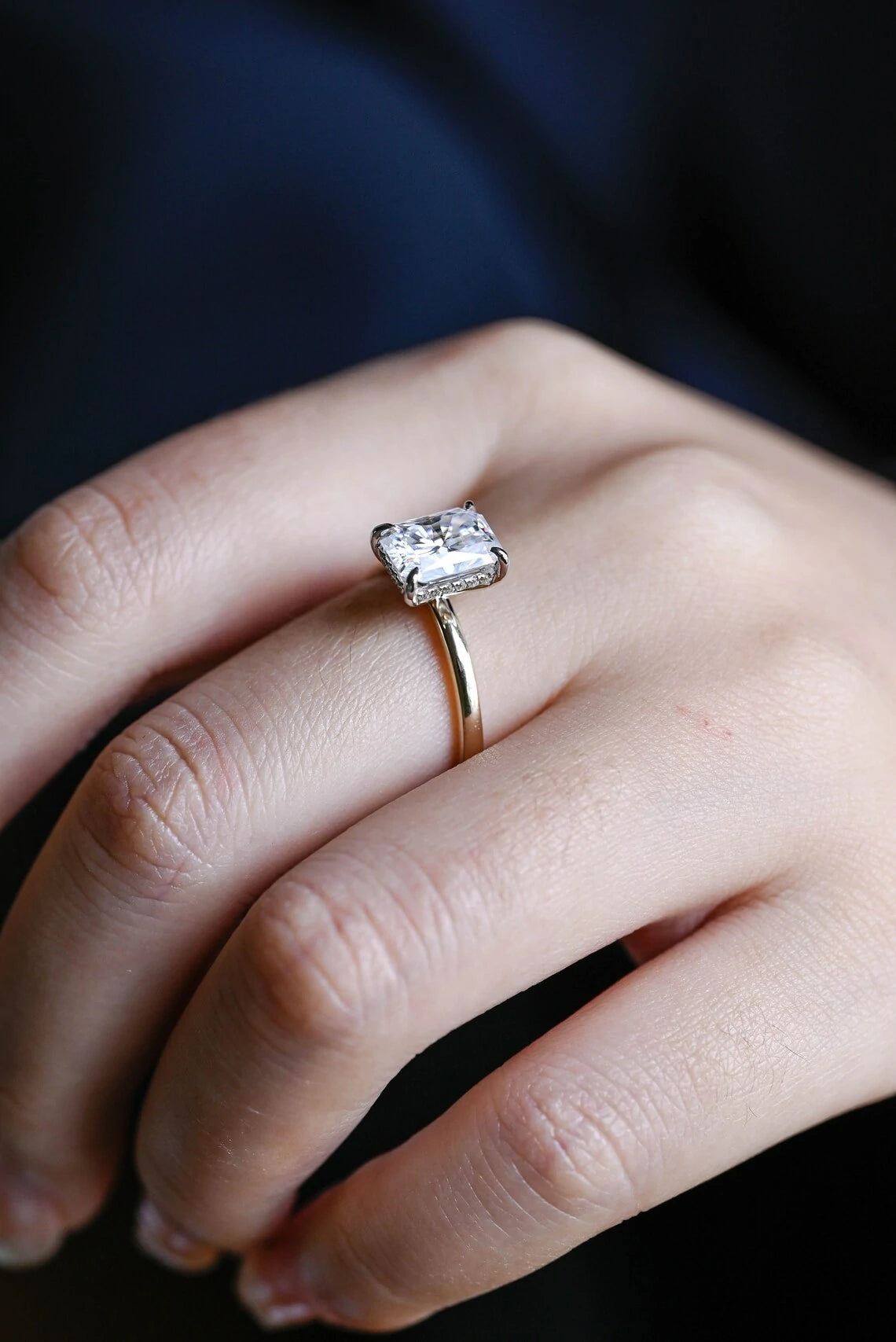 Stunning moissanite solitaire ring with radiant cut stone in yellow gold. Features a hidden halo for subtle glam and brilliant shine.