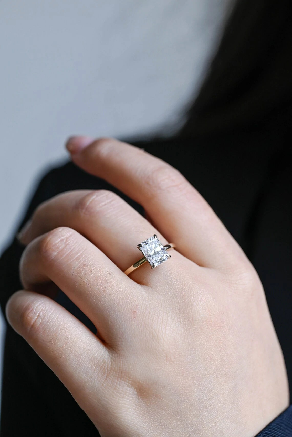 Stunning moissanite solitaire ring with radiant cut stone in yellow gold. Features a hidden halo for subtle glam and brilliant shine.