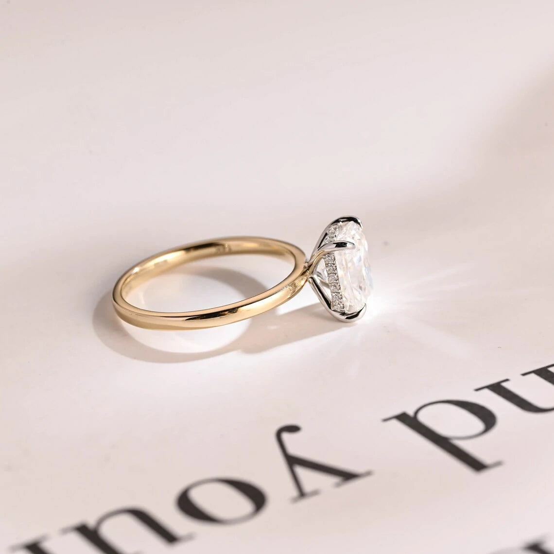 Stunning moissanite solitaire ring with radiant cut stone in yellow gold. Features a hidden halo for subtle glam and brilliant shine.