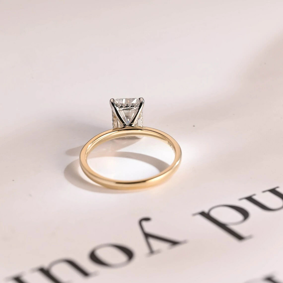 Stunning moissanite solitaire ring with radiant cut stone in yellow gold. Features a hidden halo for subtle glam and brilliant shine.