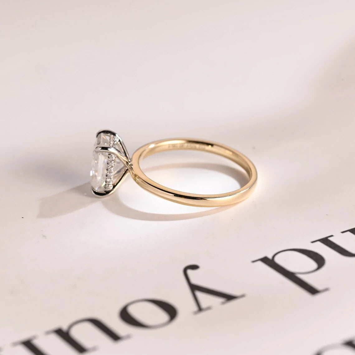 Stunning moissanite solitaire ring with radiant cut stone in yellow gold. Features a hidden halo for subtle glam and brilliant shine.