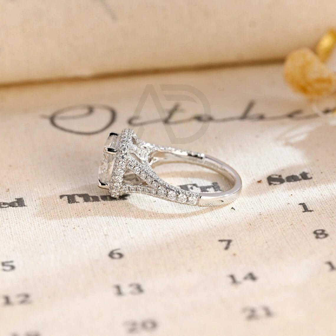 Vintage Cushion Cut Split Shank Moissanite Engagement Ring. This ring features a dazzling 3CT cushion cut moissanite diamond adorned with a halo design. Shop now!