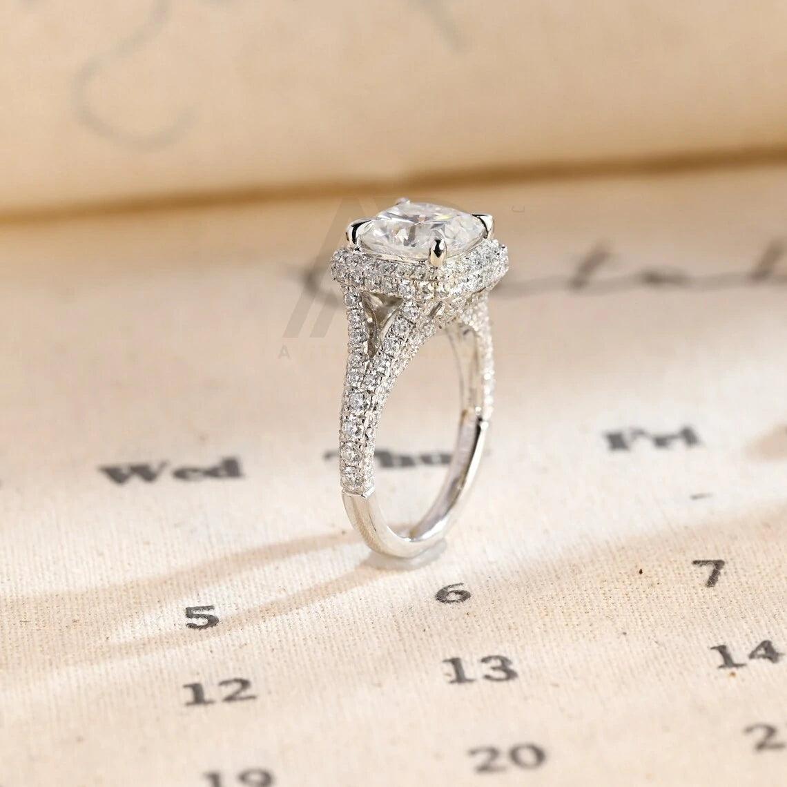 Vintage Cushion Cut Split Shank Moissanite Engagement Ring. This ring features a dazzling 3CT cushion cut moissanite diamond adorned with a halo design. Shop now!