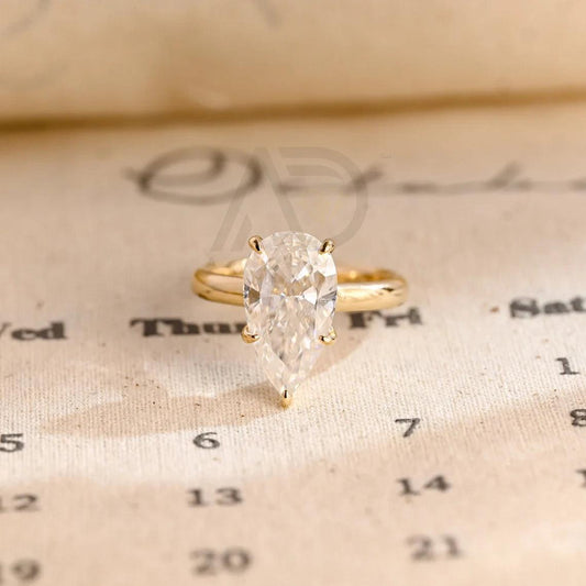 pear cut ring, moissanite engagement ring, pear shape, wedding band, bridal jewelry, unique design, halo ring, diamond alternative, anniversary gift, gold band, silver band, platinum band, handcrafted ring, dainty jewelry, elegant design, timeless beauty, luxury ring, custom made, fine jewelry, sparkling gemstone, romantic ring, statement piece, vintage style, modern elegance, designer ring