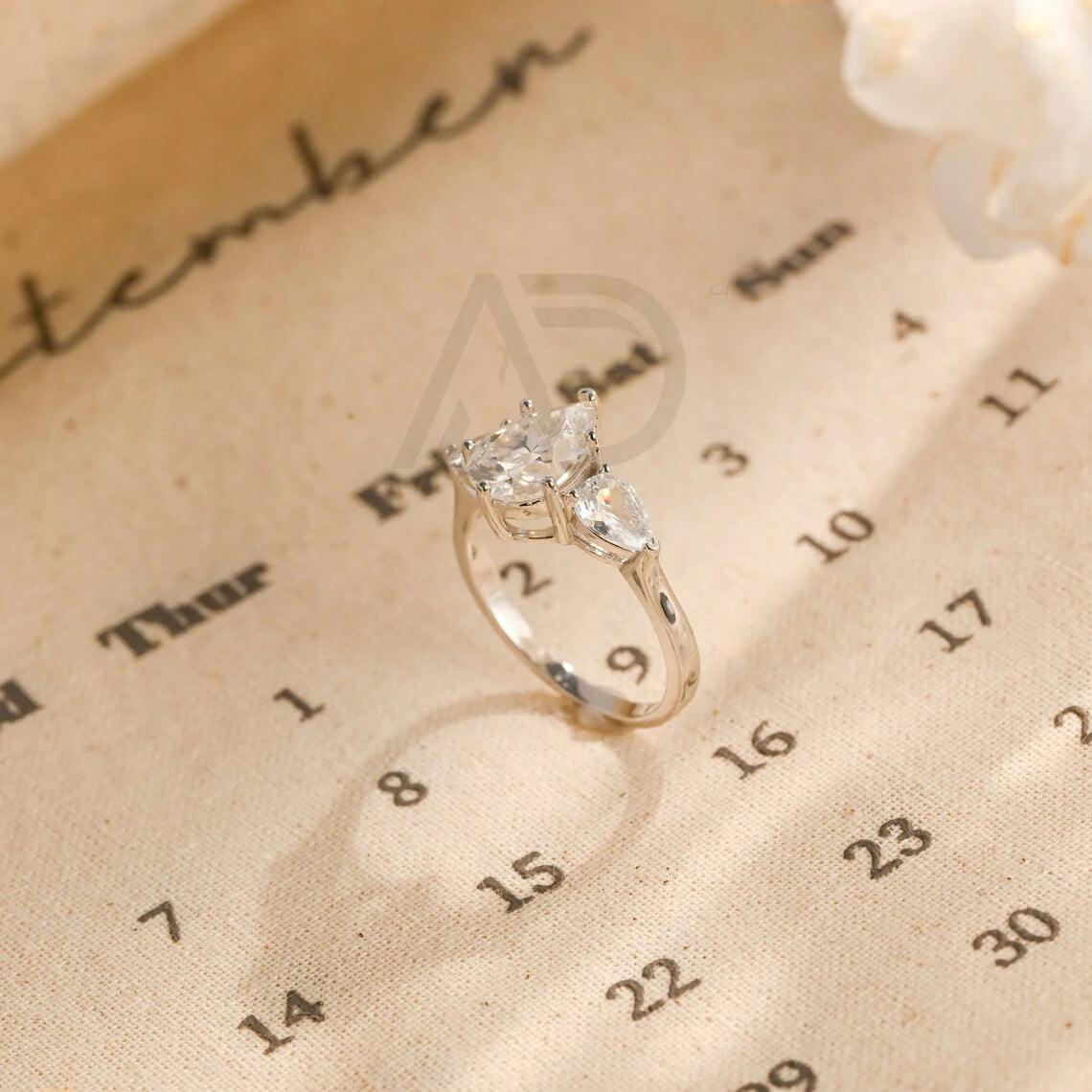 Pear Cut Three Stone Moissanite Engagement Ring. Perfect for weddings, promises, or anniversaries. Shop Now!