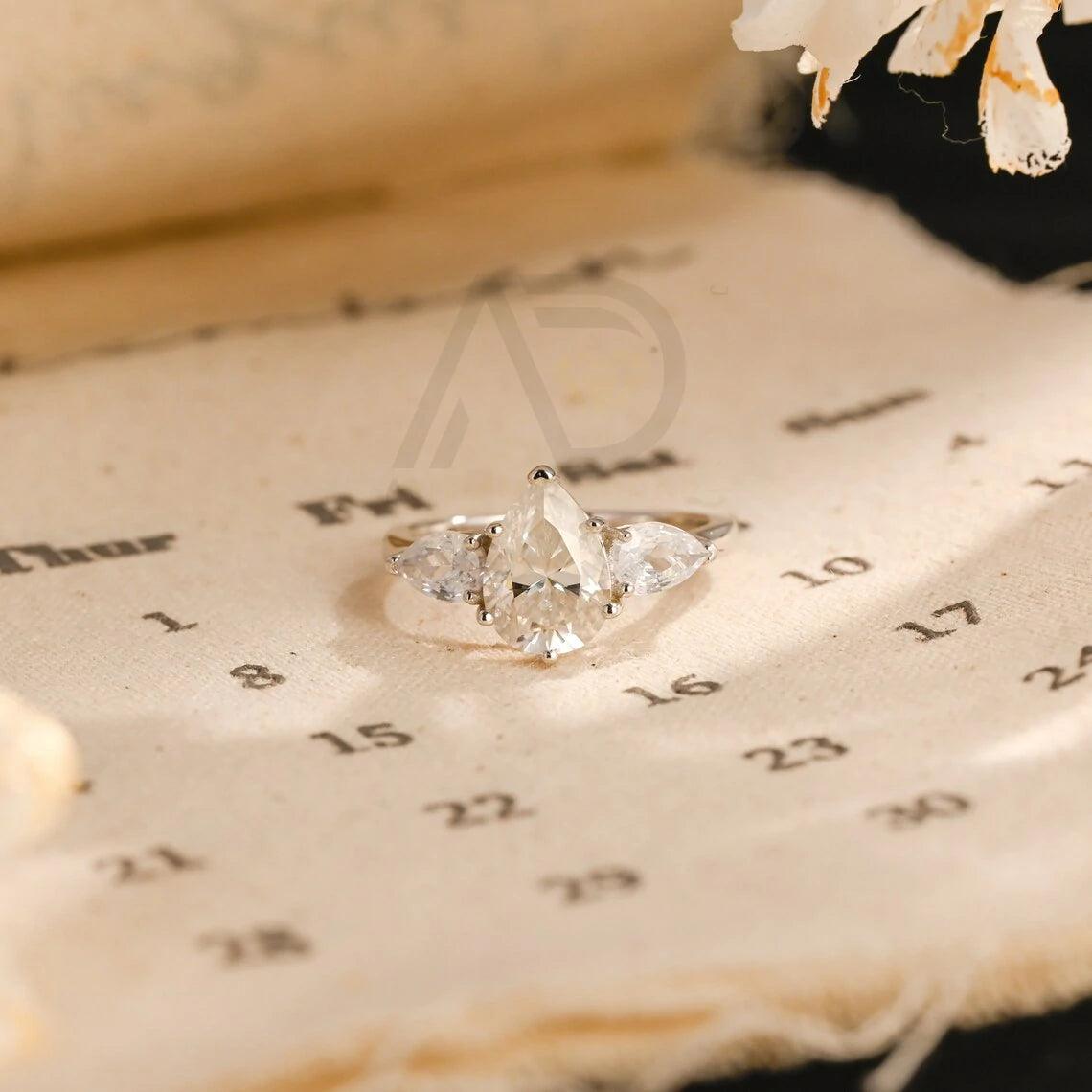 Pear Cut Three Stone Moissanite Engagement Ring. Perfect for weddings, promises, or anniversaries. Shop Now!