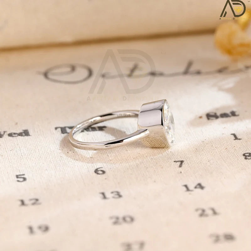 Discover our stunning Solitaire Diamond Ring with a bezel setting, featuring a captivating 14K solid gold oval cut moissanite. A perfect choice for engagement or special occasions!