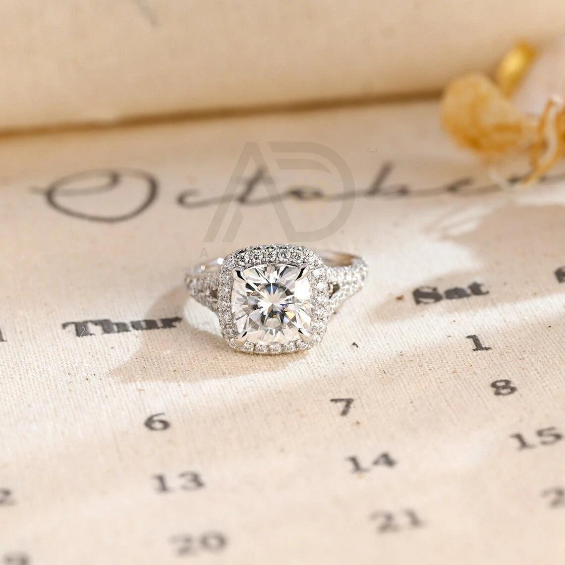 Vintage Cushion Cut Split Shank Moissanite Engagement Ring. This ring features a dazzling 3CT cushion cut moissanite diamond adorned with a halo design. Shop now!