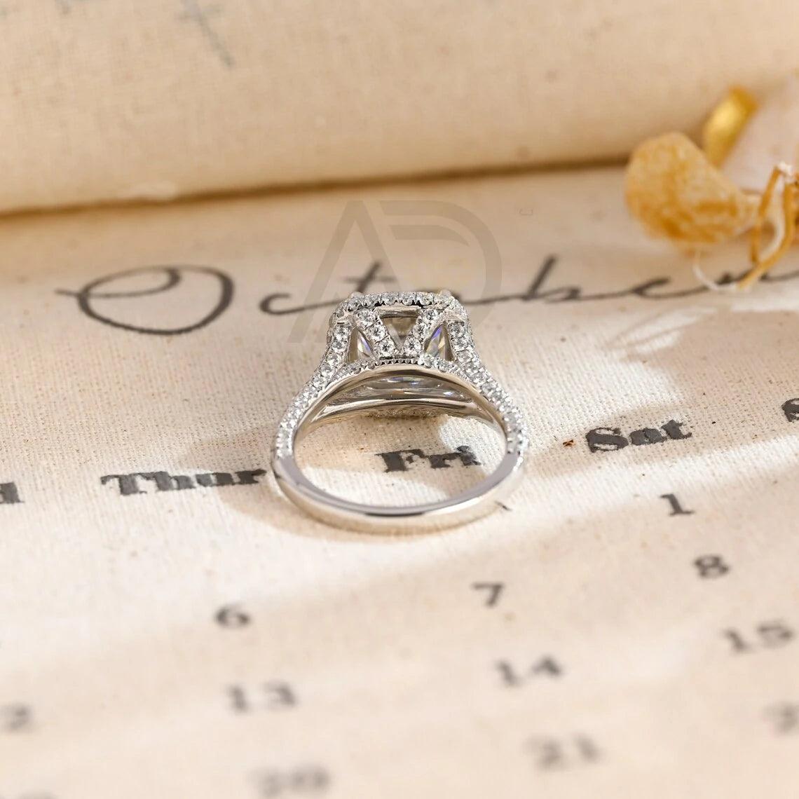 Vintage Cushion Cut Split Shank Moissanite Engagement Ring. This ring features a dazzling 3CT cushion cut moissanite diamond adorned with a halo design. Shop now!