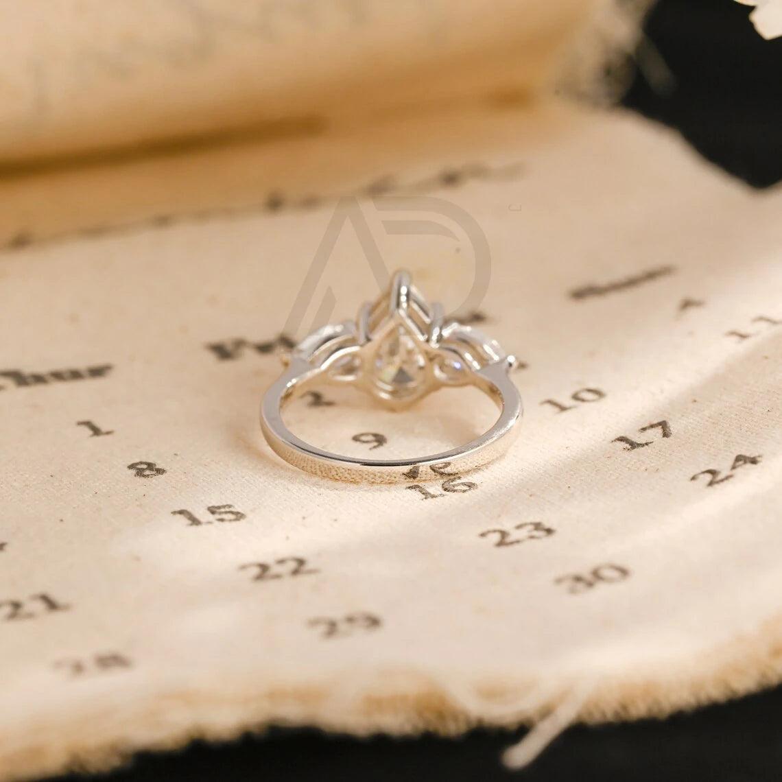 Pear Cut Three Stone Moissanite Engagement Ring. Perfect for weddings, promises, or anniversaries. Shop Now!
