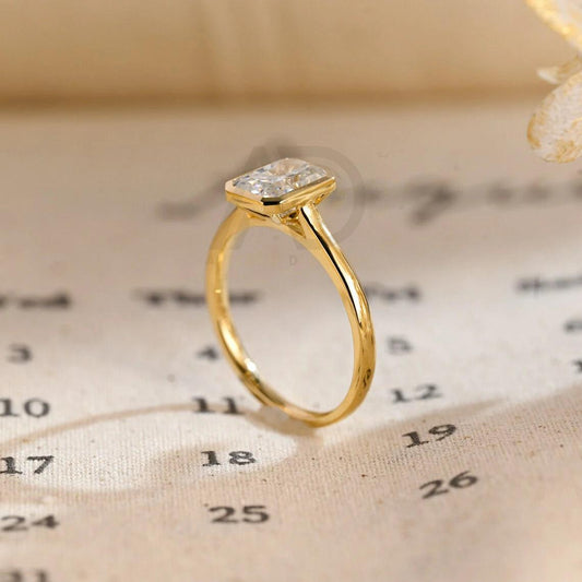 bezel radiant ring, moissanite engagement ring, radiant cut, wedding band, bridal jewelry, unique design, halo ring, diamond alternative, anniversary gift, gold band, silver band, platinum band, handcrafted ring, dainty jewelry, elegant design, timeless beauty, luxury ring, custom made, fine jewelry, sparkling gemstone, modern elegance, statement piece, designer ring