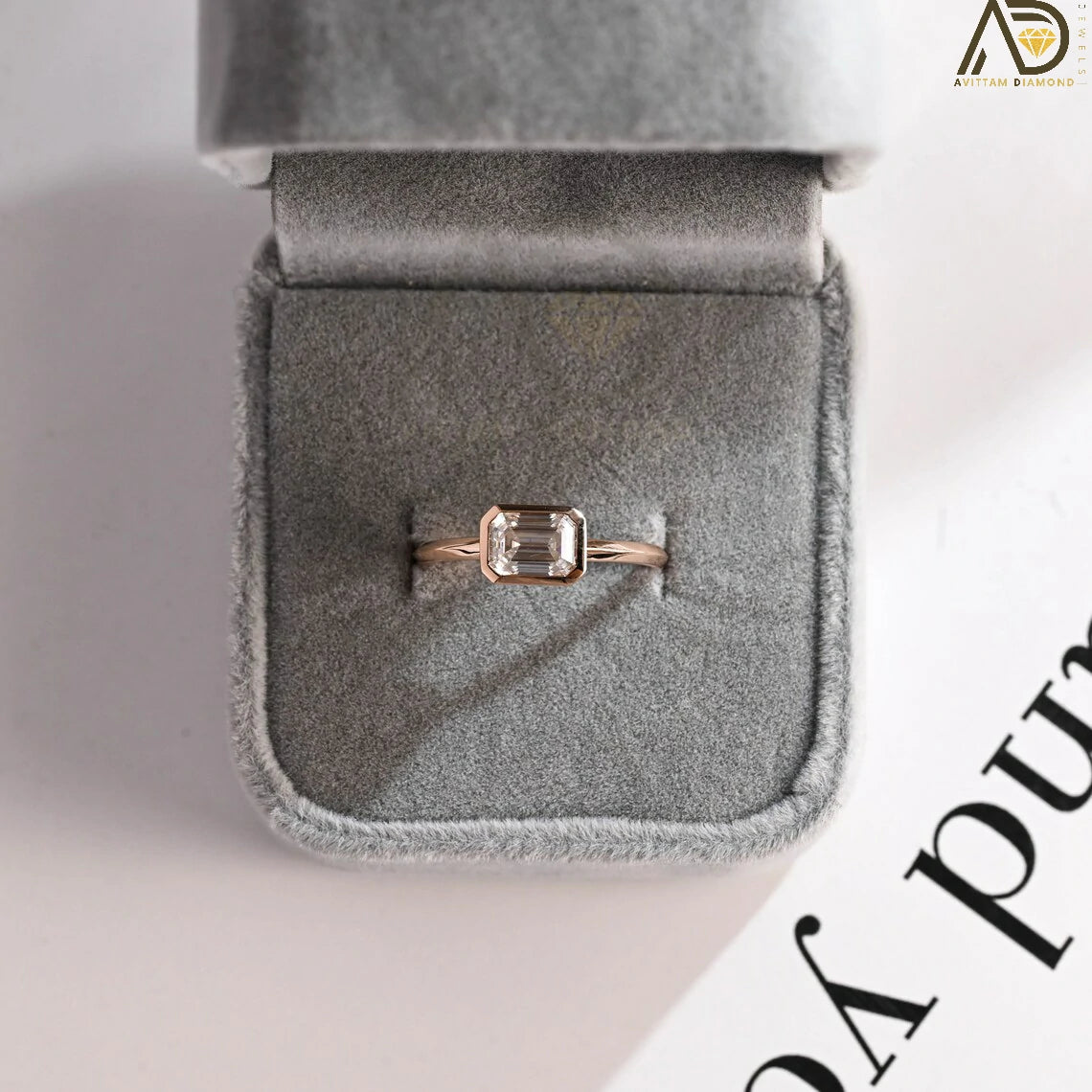 Celebrate your love with this solid gold East to West emerald cut moissanite engagement ring. Ideal for proposals, promises, anniversaries, or Christmas gifts. A stunning, timeless design for her.