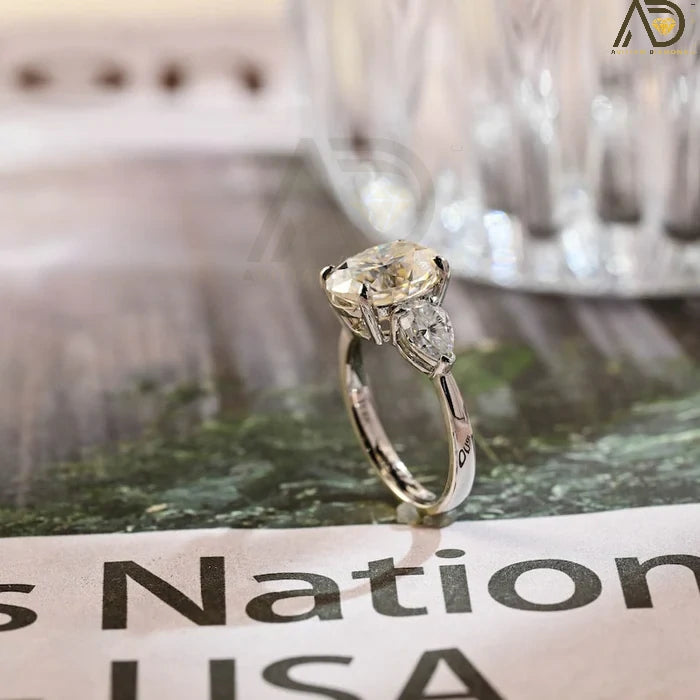 Discover our stunning Three Stone Moissanite Ring featuring an elegant oval cut center stone and pear cut side stones. A perfect choice for weddings or engagements!