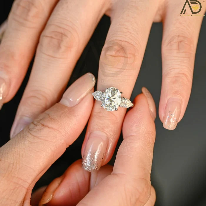 Discover our stunning Three Stone Moissanite Ring featuring an elegant oval cut center stone and pear cut side stones. A perfect choice for weddings or engagements!
