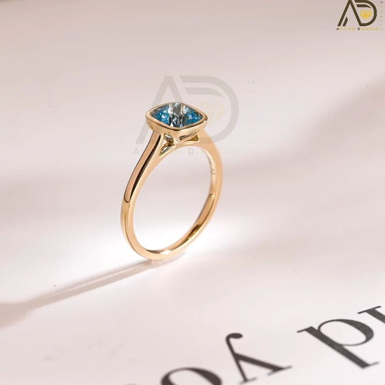Discover our Solid Gold Cushion Cut Aquamarine Engagement Ring with a sleek bezel setting. Perfect as a proposal ring, promise ring, or anniversary gift for the special woman in your life.