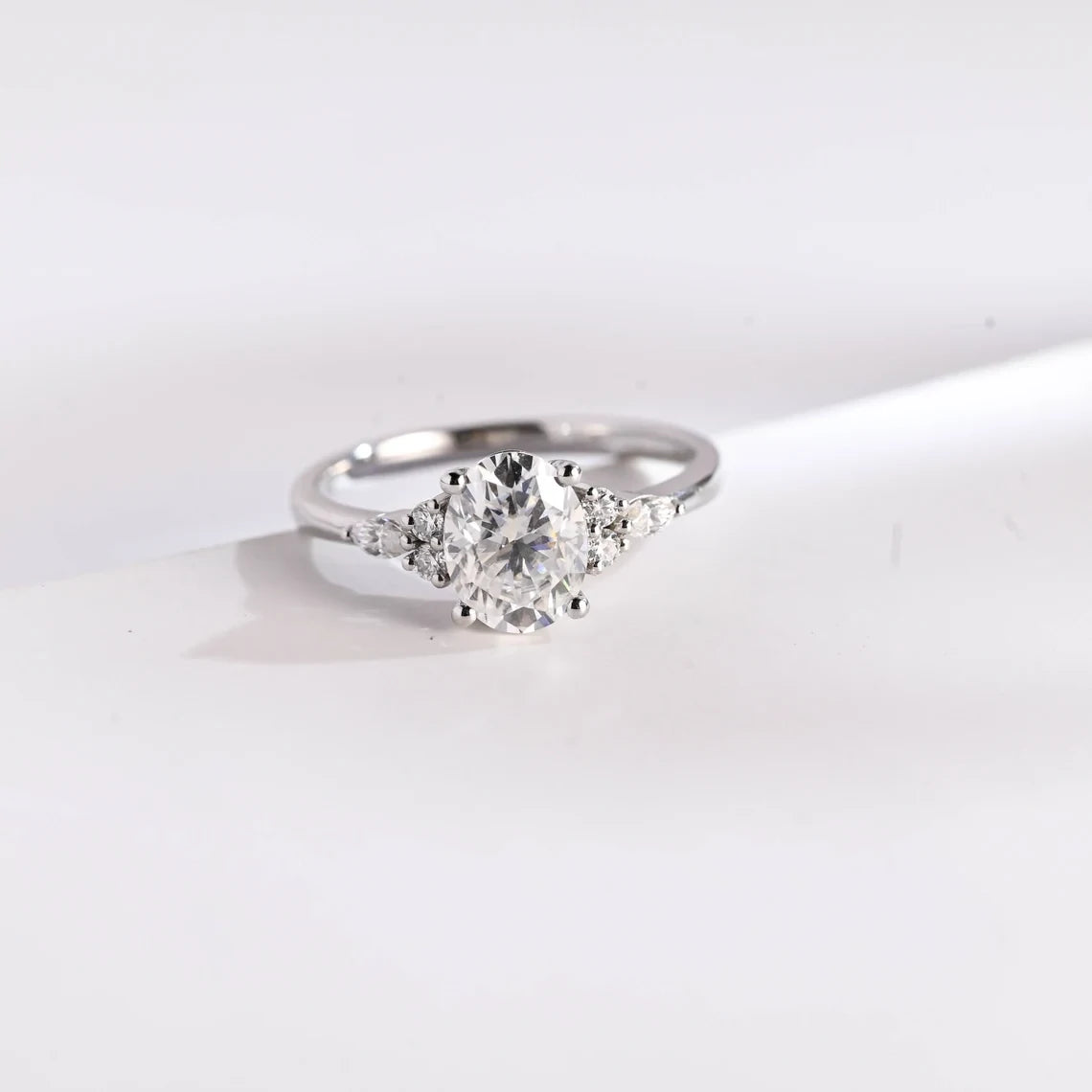 Oval Moissanite seven-stone engagement ring with pear & round cluster accents. Available in white or yellow gold, offering exceptional sparkle bridal elegance.
