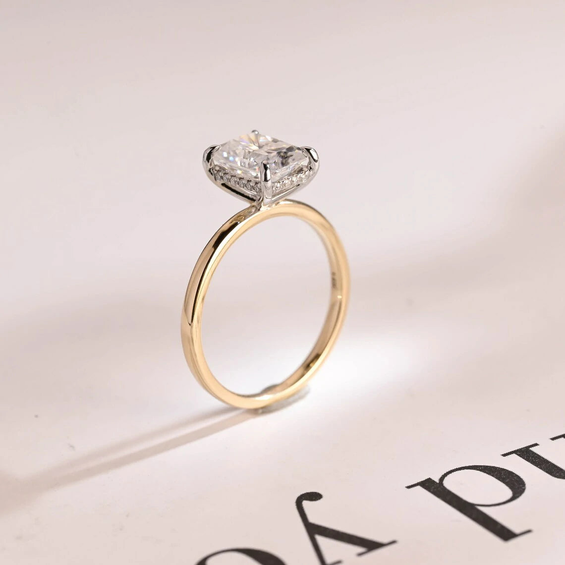 Stunning moissanite solitaire ring with radiant cut stone in yellow gold. Features a hidden halo for subtle glam and brilliant shine.