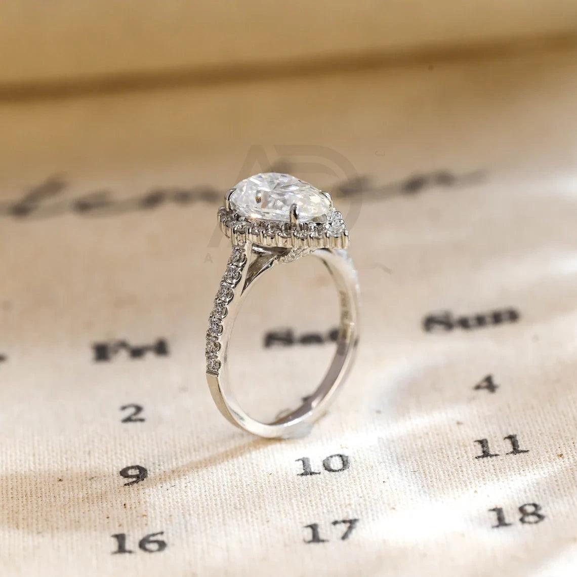 halo pear ring, pear engagement ring, pear halo ring, halo diamond ring, halo moissanite ring, pear cut ring, pear diamond ring, pear moissanite ring, halo bridal ring, pear wedding ring, halo promise ring, vintage pear ring, elegant pear ring, unique pear ring, classic pear ring, custom pear ring, gold pear ring, platinum pear ring, silver pear ring, pear eternity ring, pear three stone ring, halo anniversary ring, luxury pear ring, dainty pear ring, simple pear ring