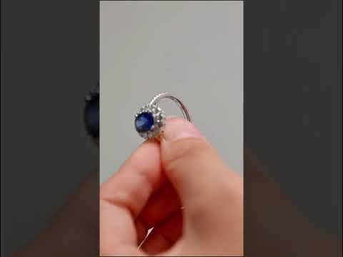 Royal blue oval cut moissanite diamond halo ring set in white gold. Half eternity pave blue center stone, timeless engagement or anniversary piece.