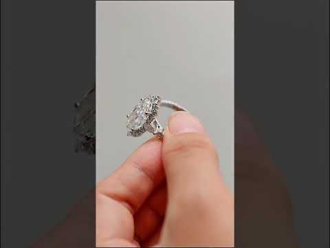 Oval cut moissanite halo ring with pear and round side stones on a half-eternity pave. A luxurious cluster engagement ring with exceptional sparkle.